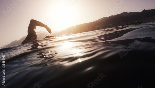 Athletic young man swimming at sea. Professional triathlon swimmer in water