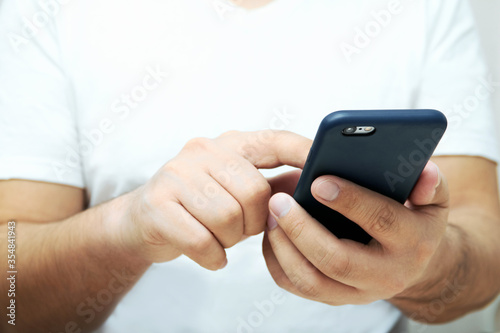 A person is holding a phone and tapping the screen on a white background with copy space. Concept of lifestyle business and Internet technologies in the office