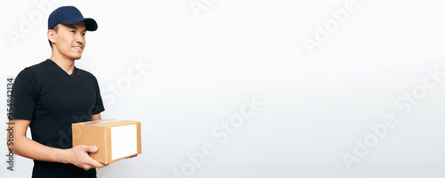 An Asian courier holds a box with copy space on a white background. Concept of a business service for food delivery during quarantine and the COVID-19 virus