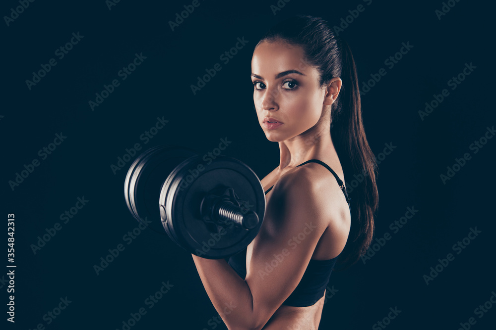 Close up photo of lovely serious girl hold hand barbells look want be slender isolated over black background Close up photo of lovely serious girl hold hand barbells look want be slender isolated over black background