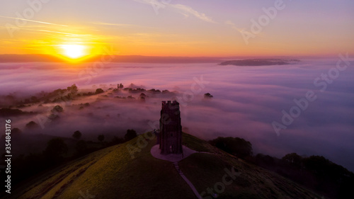 Early morning sunrise over Glastonbury Tor and the misty fields, Somerset. photo