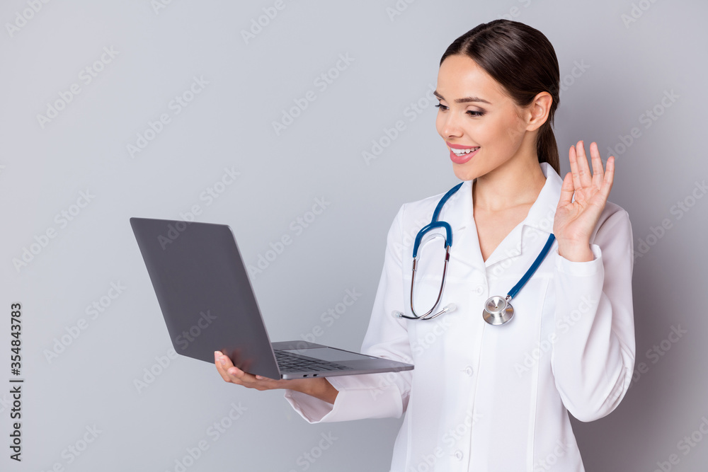 Photo of professional family doc lady browsing modern technology notebook greeting patients online video examination wear stethoscope white lab coat isolated grey color background Photo of professional family doc lady browsing modern technology notebook greeting patients online video examination wear stethoscope white lab coat isolated grey color background