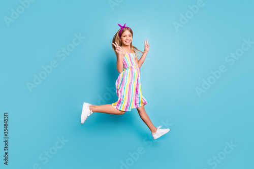 Fototapeta Naklejka Na Ścianę i Meble -  Full length body size view of her she nice attractive lovely small little cheerful cheery girl jumping showing v-sign isolated over bright vivid shine vibrant blue color background