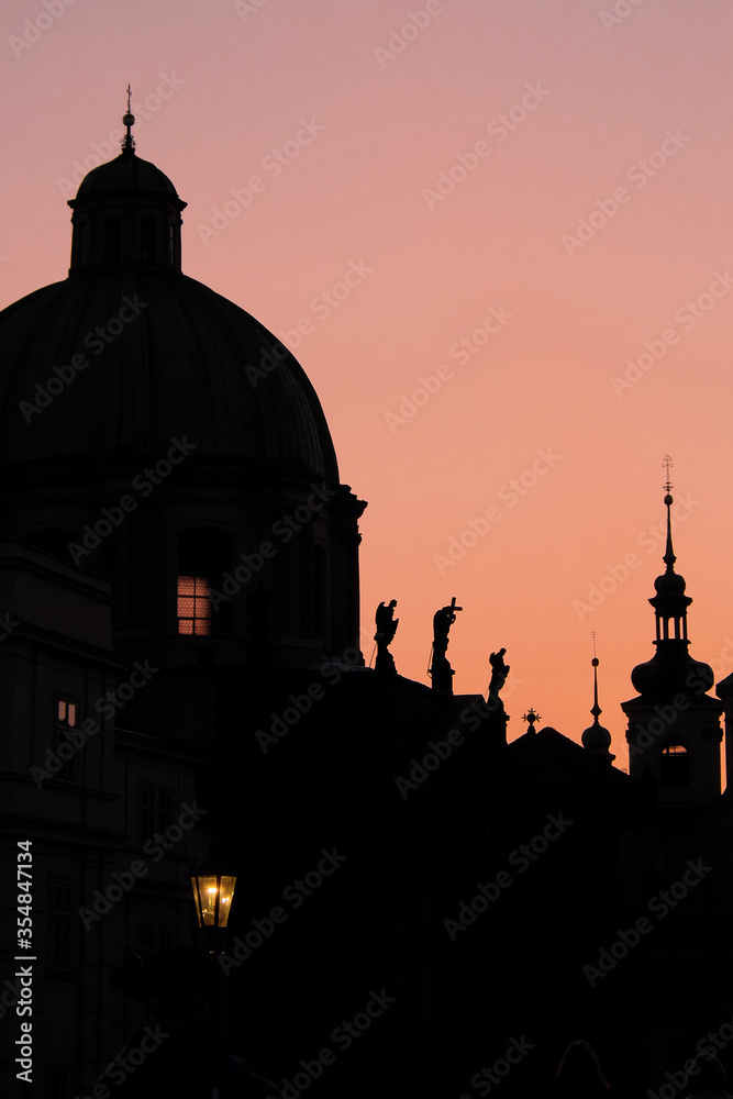 Silhouettes of ancient European buildings on a pink sky background.