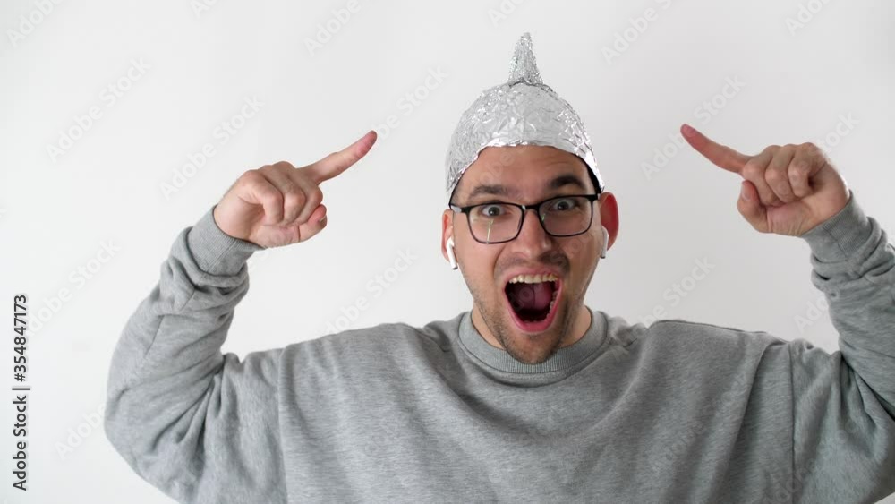 White man in a foil hat smiles and joyfully points his fingers at the ...
