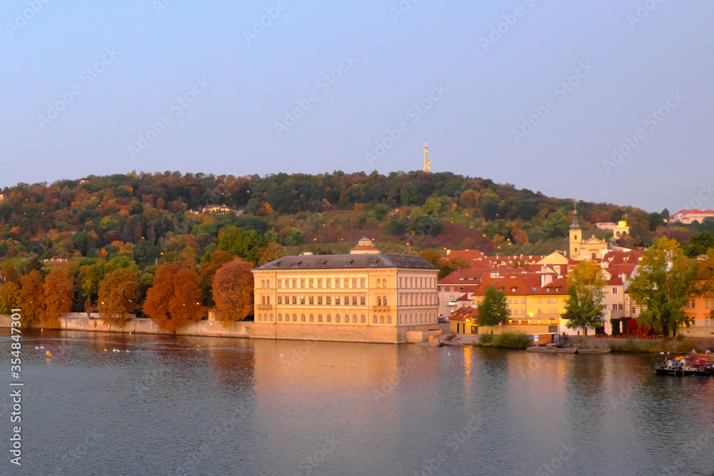 Obraz premium Picturesque Prague embankment in the fall. Forested hill.