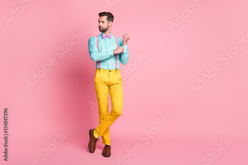 Full length photo of handsome guy trend clothes preparing corporate meeting well-dressed wear teal shirt suspenders bow tie yellow trousers boots socks isolated pastel pink color background