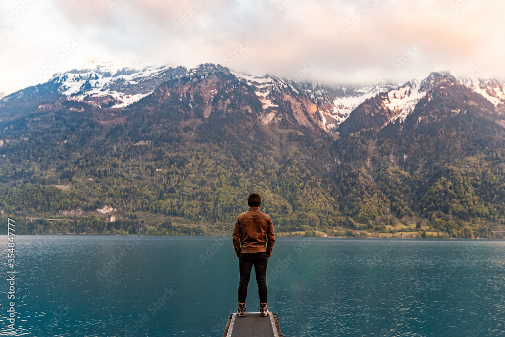 Man on the lake overlooking Switzerland mountains