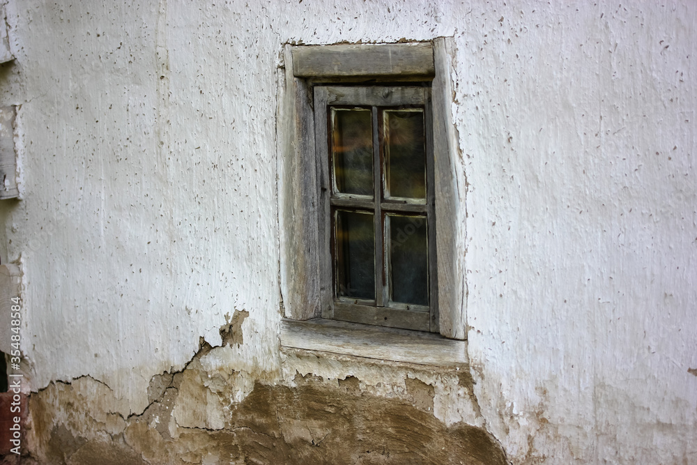 An old cracked window frame in a white house in the village