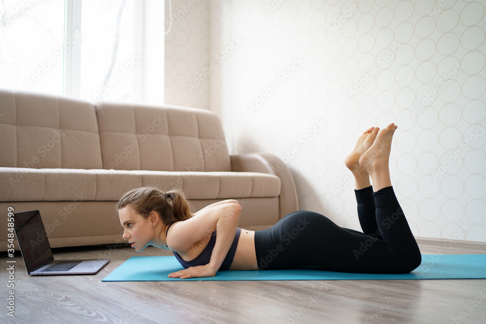 Fototapeta premium beautiful girl is engaged in sports online at home on the laptop. 