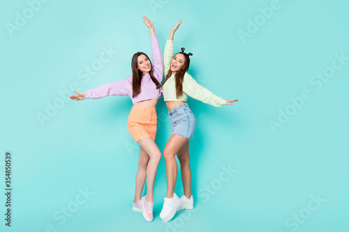 Fototapeta Naklejka Na Ścianę i Meble -  Full length body size of two nice attractive fashionable pretty cheerful cheery girls having fun posing celebrating isolated over bright vivid shine vibrant blue green turquoise color background
