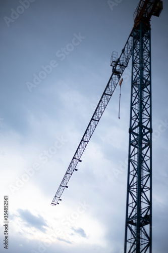 Tower crane with dark blue sky at twilight. Vertical shot, building background or wallpaper.