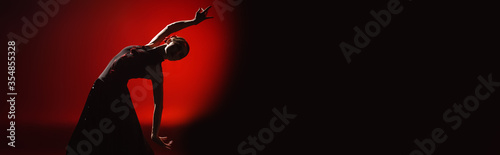 panoramic orientation of young woman dancing flamenco on red and black photo