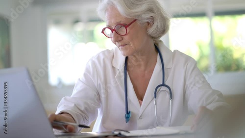 Senior woman doctor working on laptop photo