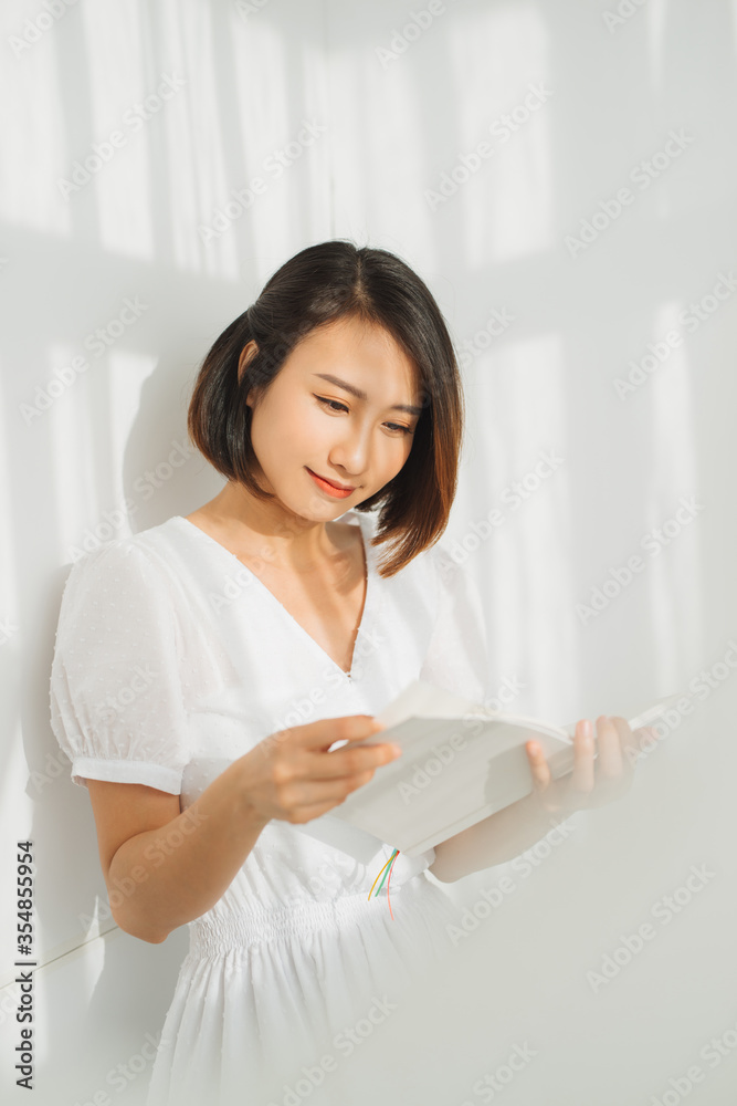 Portrait of beautiful asian woman relaxing by reading book near the window with sunlight of the morning Portrait of beautiful asian woman relaxing by reading book near the window with sunlight of the morning