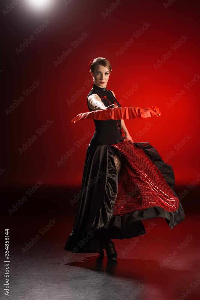 elegant woman in dress holding fan while dancing flamenco on red elegant woman in dress holding fan while dancing flamenco on red