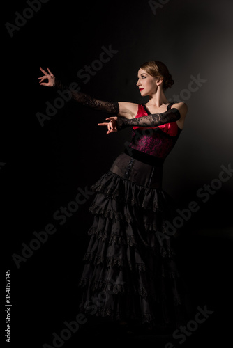 elegant woman gesturing and dancing flamenco on black