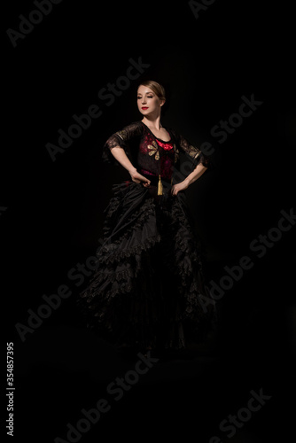 elegant and beautiful flamenco dancer with hands on hips isolated on black