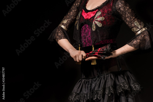 cropped view of young flamenco dancer holding fan isolated on black