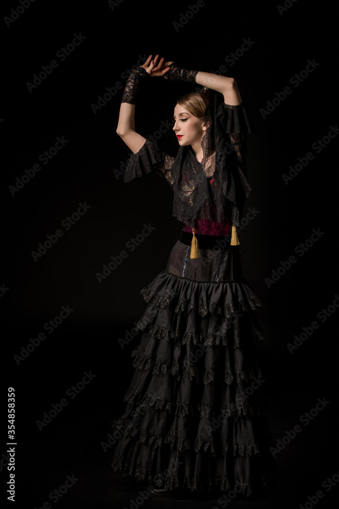 attractive dancer with hands above head dancing flamenco isolated on black