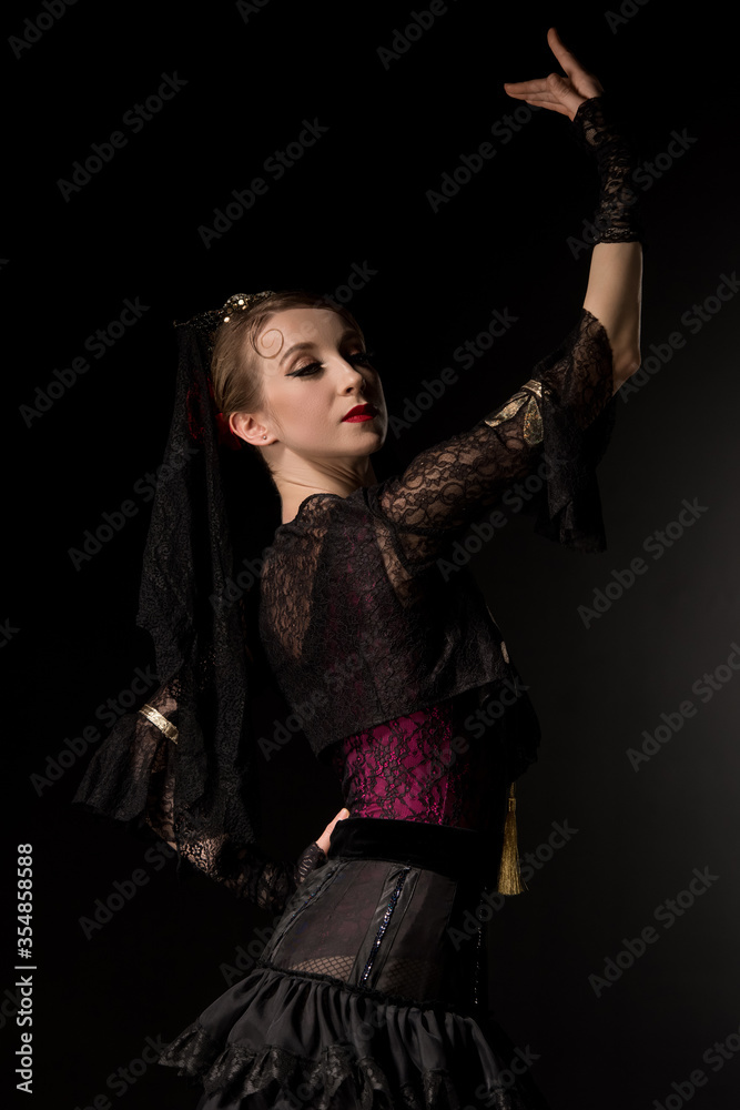 beautiful dancer looking at camera while dancing flamenco isolated on black
