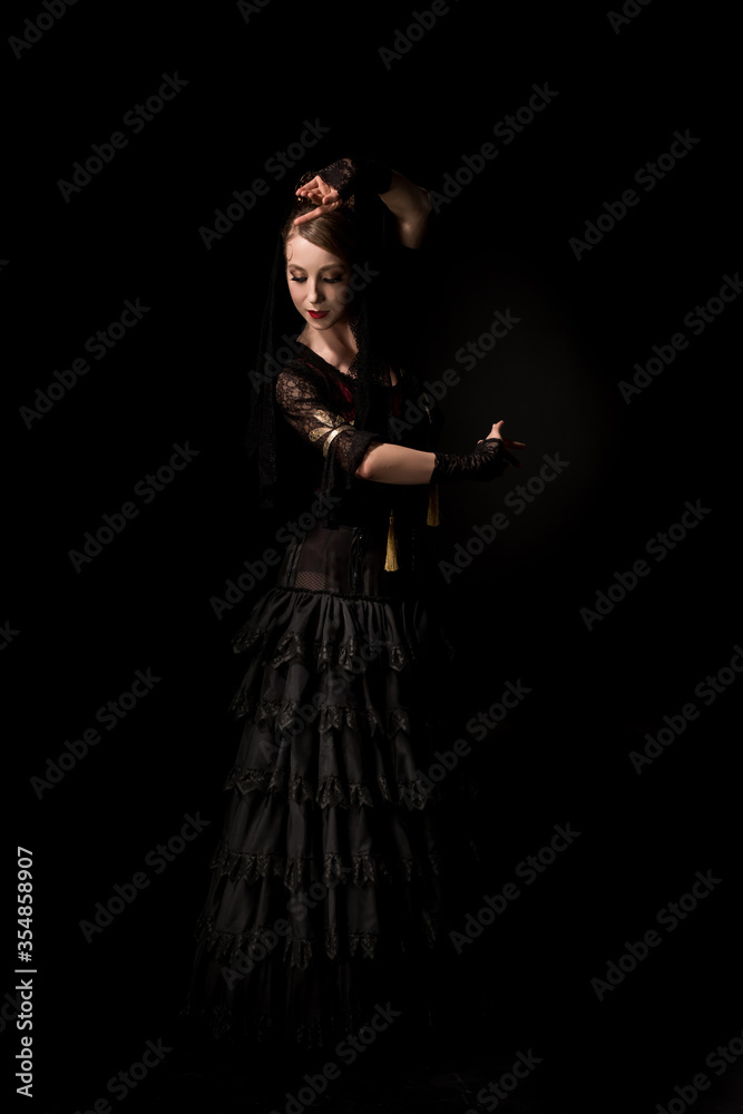 pretty young flamenco dancer dancing in dress isolated on black