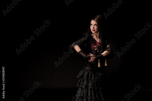 pretty young flamenco dancer standing isolated on black