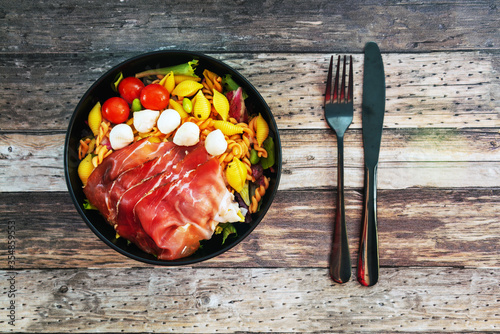 Salad made with cooked pasta, mixed green salads, cherry tomatoes, Mozzarella cheese and smoked ham served with accompaniment