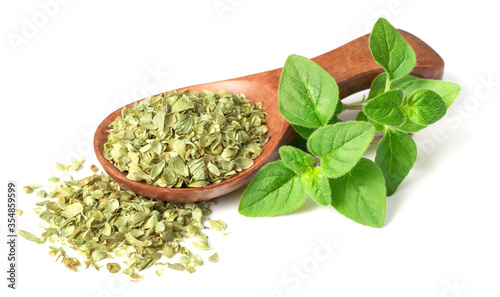 dried oregano flakes in the wooden spoon, with fresh oregano twigs, isolated on white background