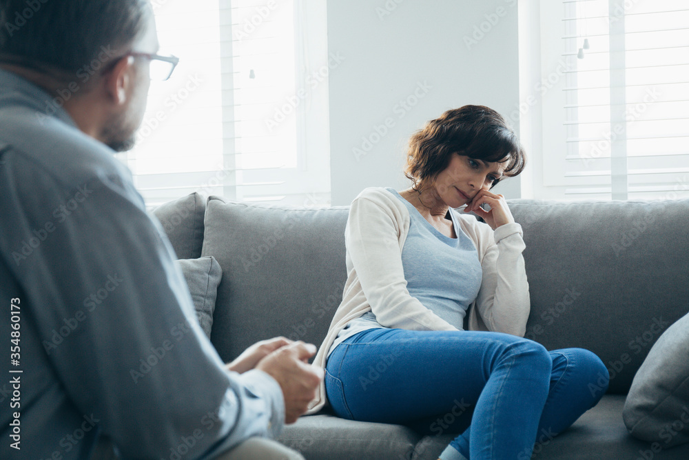 Beautiful woman sitting on a gray sofa during a meeting with a psychotherapist