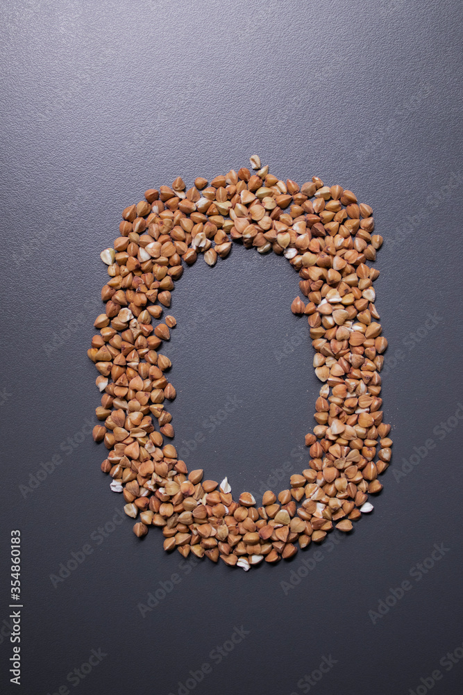 Obraz premium Letter 'o' written with buckwheat On gray background, top view, copy space. Food supplies crisis, food donation on quarantine isolation period