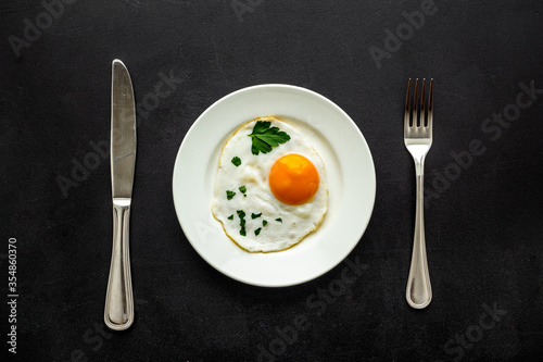 Fried eggs on plate - black table from above