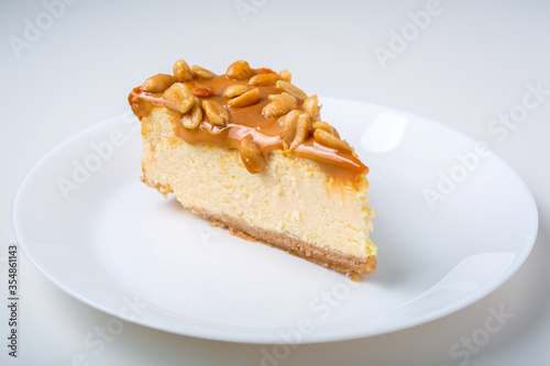 Piece of cheesecake with caramel and peanuts coating