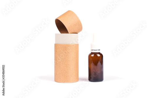 Bottle of essential oil, collagen or hyaluronic acid with paper tube packaging isolated on white. Mockup and copyspace for your design or text. Modern beauty and apothecary concept photo