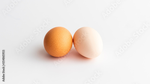 One is brown and the other is white, two eggs on the white background 
