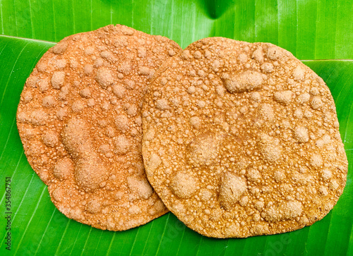 Dried crunchy rotten beans sheet stacking on fresh green banana leaf. Northern Thailand culture ingredient for cuisine.