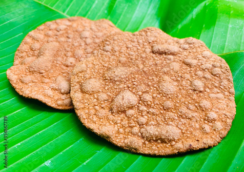 Dried crunchy rotten beans sheet stacking on fresh green banana leaf. Northern Thailand culture ingredient for cuisine.