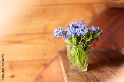 Forget-me-nots in a vase on a wooden background.