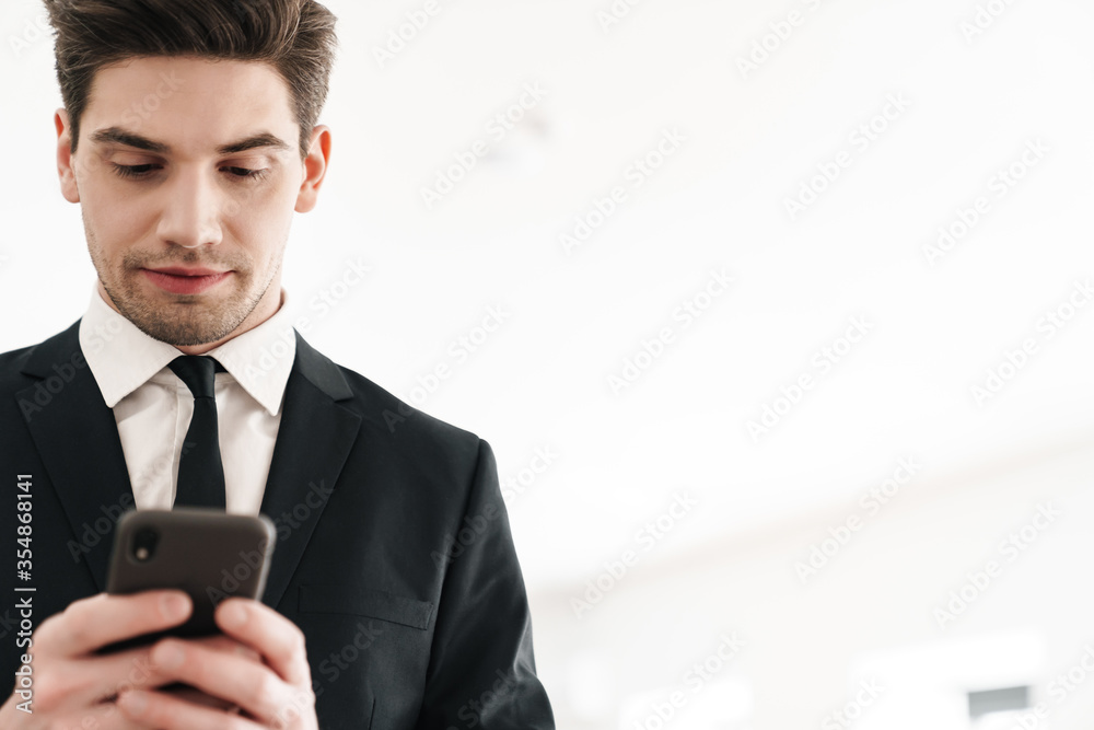 Image of serious businessman wearing black suit using mobile phone Image of serious businessman wearing black suit using mobile phone