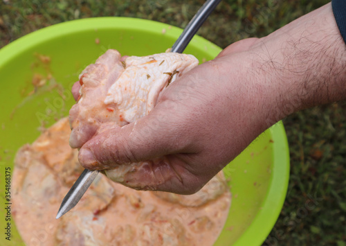 Delicious chicken skewer on a spit in the hand of a man, close-up