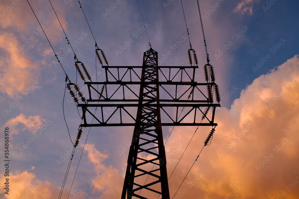 Electricity transmission tower with sunset sky on background.