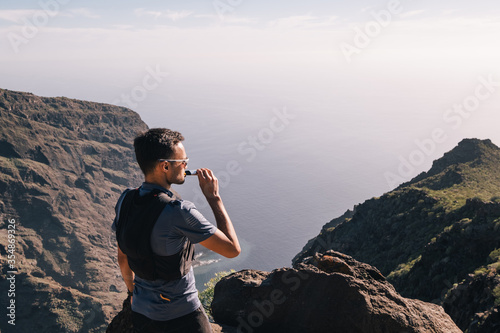 Portrait of young man drinking energy sports nutrition energy gel while sitting and resting after trail running