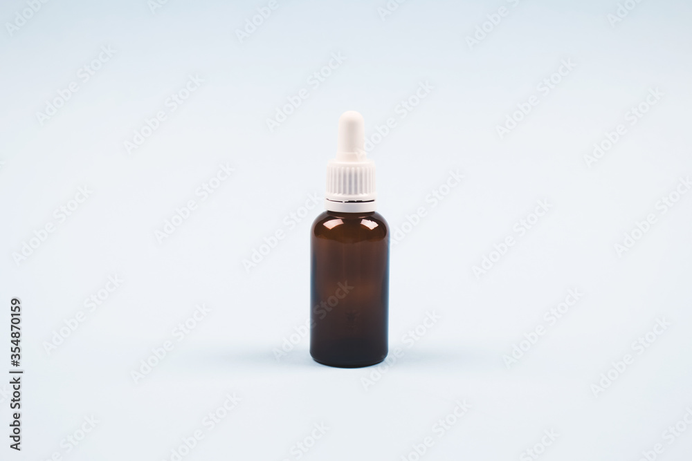 Bottle of essential oil, collagen or hyaluronic acid on light blue background. Mockup and copyspace for your design or text. Modern beauty and apothecary concept