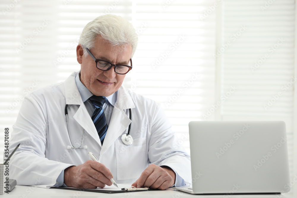 Senior doctor working at table in office Senior doctor working at table in office