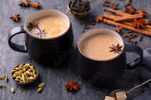 Indian masala tea with milk and spices in mug. Grey background. Close up.