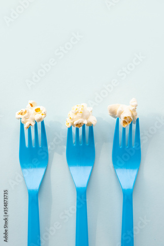 Tasty salted popcorn on blue plastic forks with copy space for text. Minimalistic food concept. Close up, top view and shooting in studio.