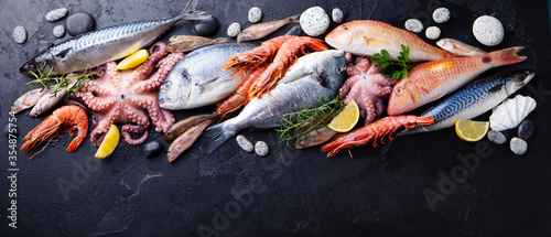 Tableau sur toile Fresh fish and seafood assortment on black slate background