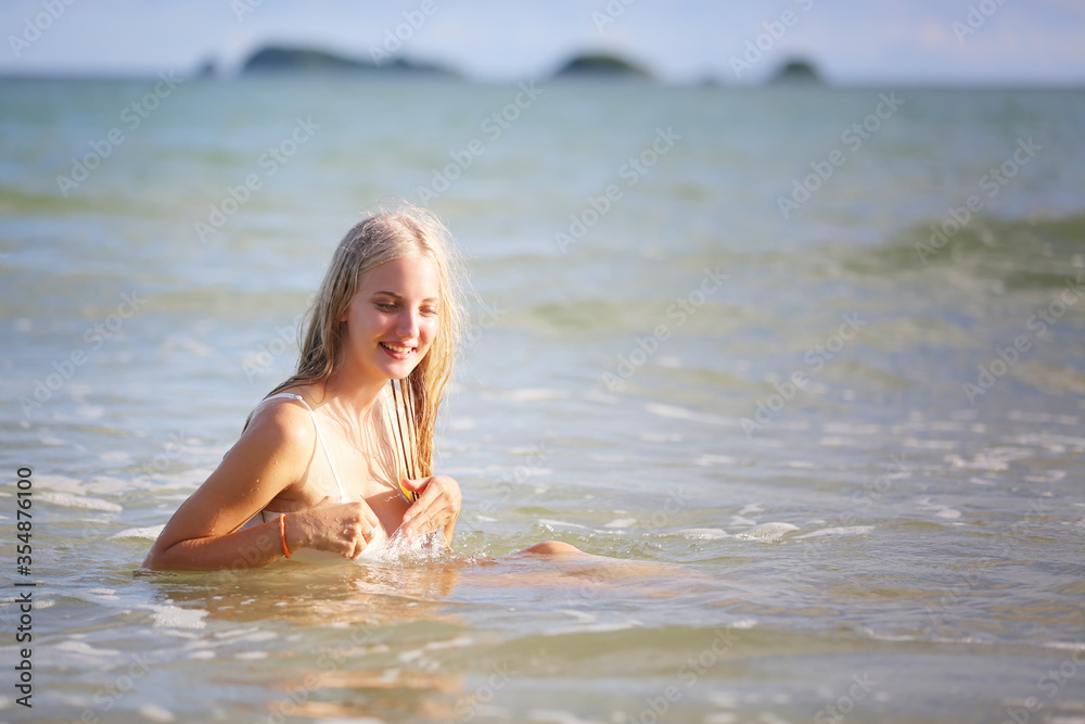 Smiling woman in bikini lying on tropical beach, happy female in swimwear white color enjoying summer holidays lying on white sand against blue sky. Holidays, vacation, lifestyle concept. Copyspace Smiling woman in bikini lying on tropical beach, happy female in swimwear white color enjoying summer holidays lying on white sand against blue sky. Holidays, vacation, lifestyle concept. Copyspace
