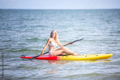 Woman paddling a kayak by the tropical beach. Kayaking tour in Phuket, Thailand, woman relaxing in a kayak Summer seascape beach and blue sea water © FotoArtist