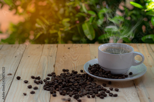 A coffee cup placed on a wooden background with a tree bokeh